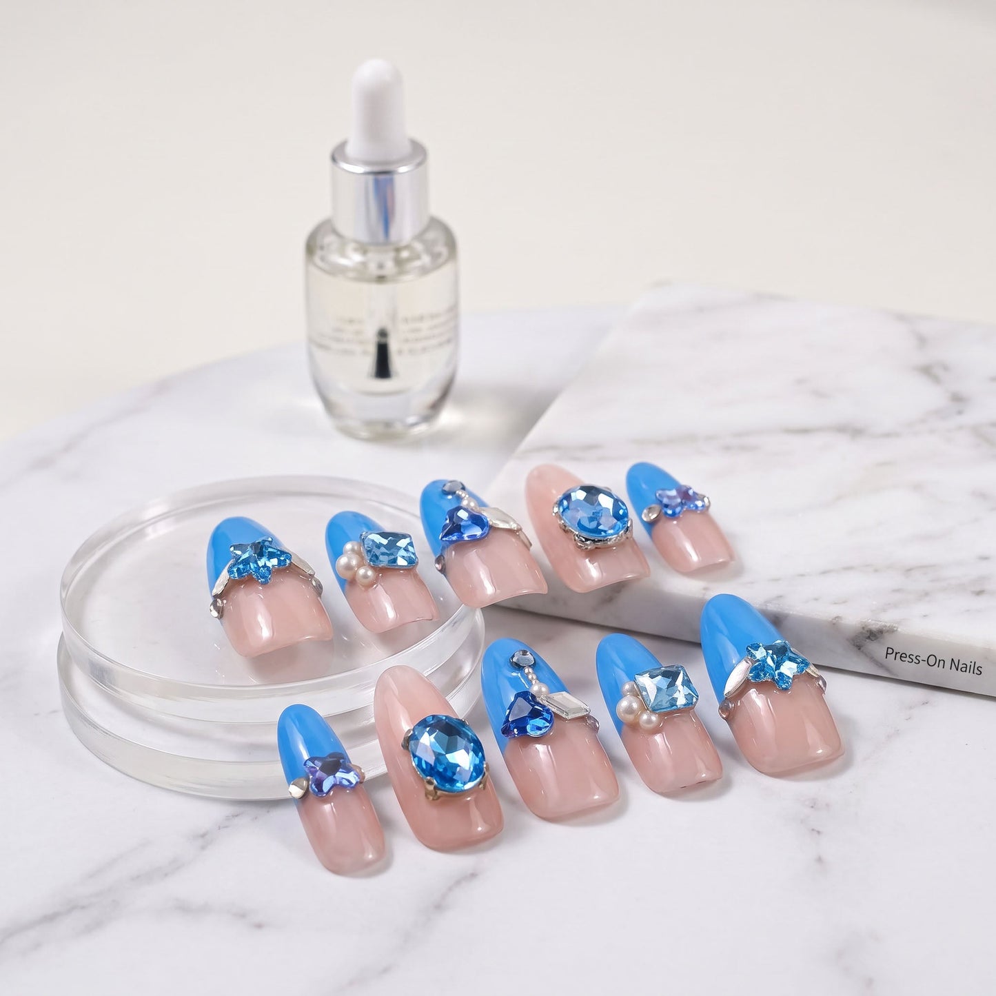 Fun Blue press-on nails with bright blue colour, nude pink sections and blue crystal embellishments