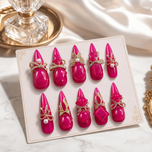 Pink Voltage handmade press-on nails in vivid fuchsia with ornate gold bows, butterflies and pearls